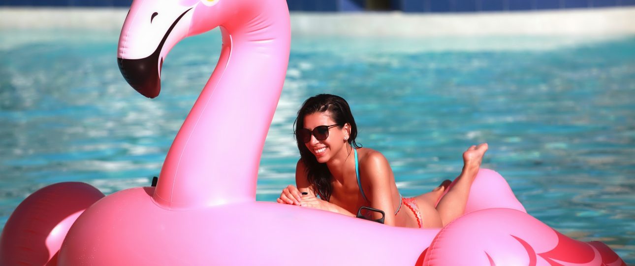 Mujer flotando en flamingo inflable intex en la playa