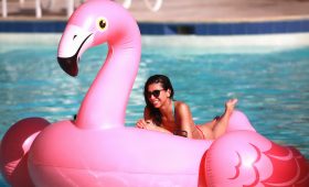 Mujer flotando en flamingo inflable intex en la playa